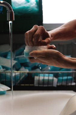 Cerrahi bir odada cerrahi müdahale. Ameliyattan önce musluğun altında ve lavabonun üstünde cerrahi süngerle çivi fırçalamak.