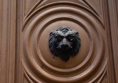 Antika bir kapının ahşap yapısına sabitlenmiş aslan başı şeklinde antik bir metal yapı..