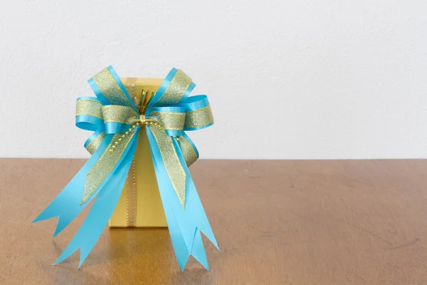 The big blue bow yellow gift box on the wood — Stock Photo, Image