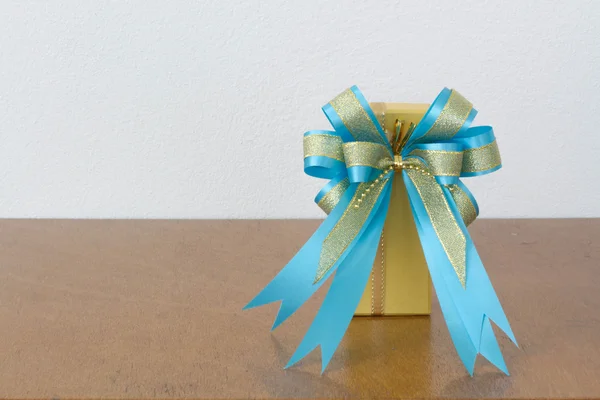 The big blue bow yellow gift box on the wood — Stock Photo, Image