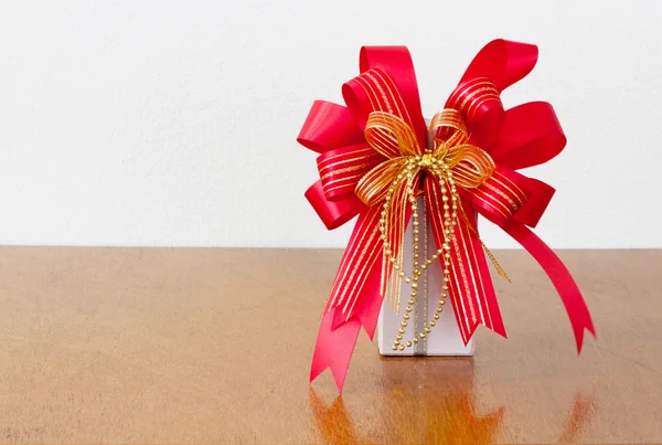 The big red bow white gift box on the wood — Stock Photo, Image