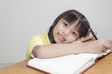 Asyalı kız çocuk mutlu çalışma notları beyaz kağıt kitap yazma onun elinde onun kalem ile oturma odasında