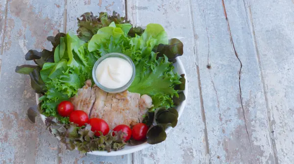 Filete de cerdo saludable servido con tomates y verduras frescas para ensaladas en una tabla de madera vieja — Foto de Stock