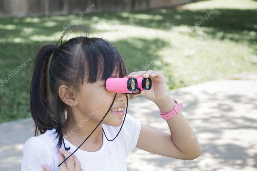 Young girl looking in binoculars and smile