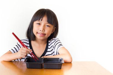 Neşeli çocuk kız masada oturan kırmızı yemek çubukları ile