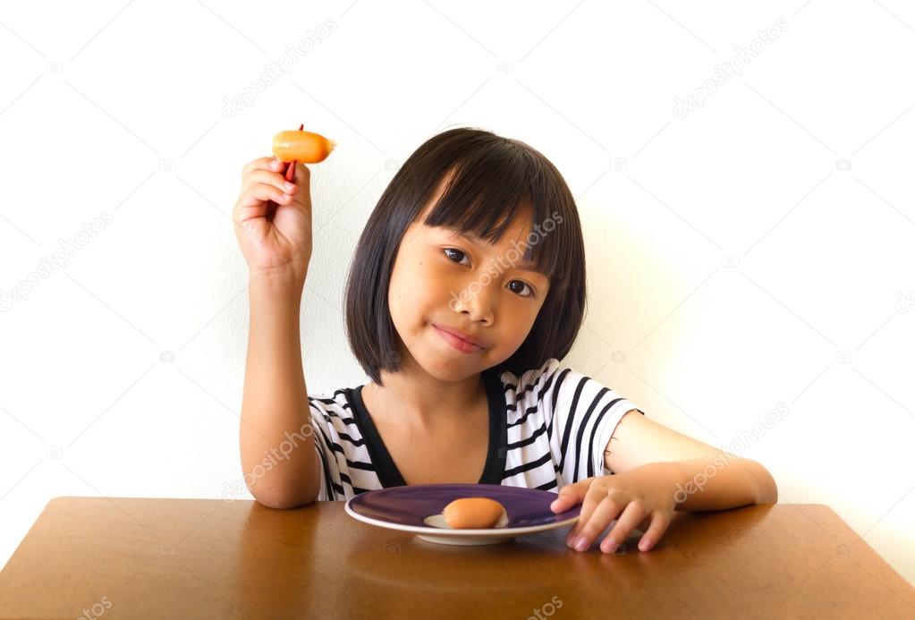 Joyful children girl with red chopsticks sitting at the table