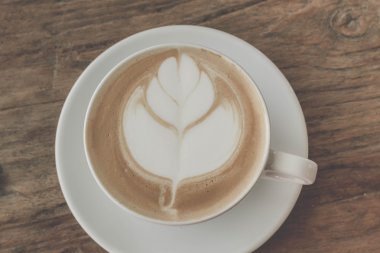 Bir fincan kahve latte sanat eski ahşap arka plan - Vintage filtre efekti üzerinde kapatın