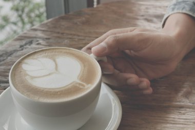 Bir fincan kahve latte sanat eski ahşap arka plan - Vintage filtre efekti üzerinde kapatın