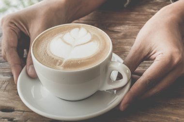 Bir fincan kahve latte sanat eski ahşap arka plan - Vintage filtre efekti üzerinde kapatın