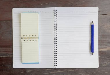 Boş defter ve kalem eski ahşap ofis masasında.