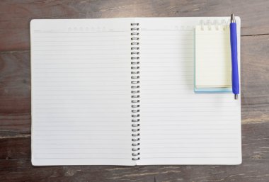 Boş defter ve kalem eski ahşap ofis masasında.
