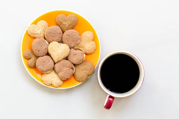 Chocolate cookies and butter cookies on white dish with black coffee