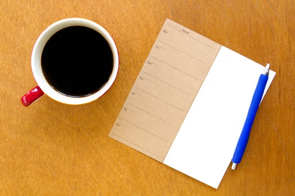 内存空白笔记本和蓝色钢笔用木制背景上咖啡 — 图库照片