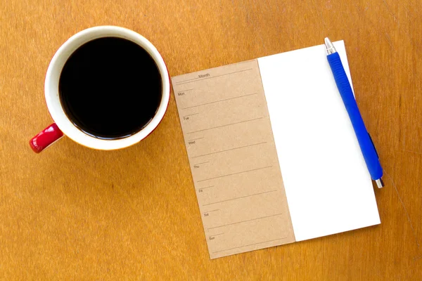 内存空白笔记本和蓝色钢笔用木制背景上咖啡 — 图库照片