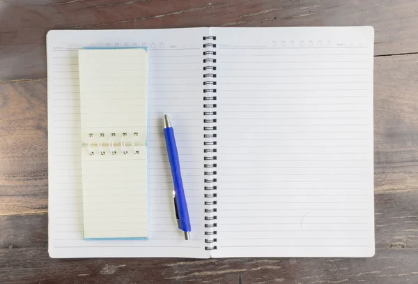 Caderno em branco e caneta na velha mesa de escritório de madeira . — Fotografia de Stock
