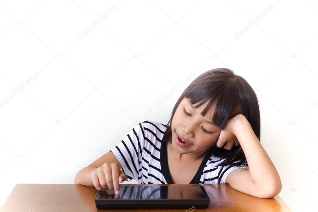 Little girl with joyful tablet pc sitting on the wooden table - Technology and children concept