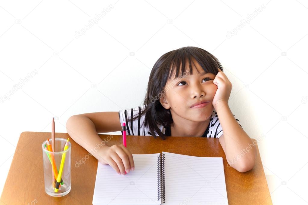 Little asian girl drawing with colorful pencil sitting on the wooden table