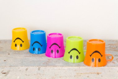 Çeşitli renk ahşap arka plan üzerinde gülümseyen, plastik bardak