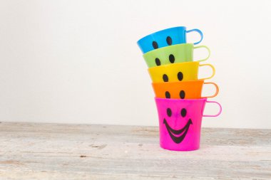 Çeşitli renk ahşap arka plan üzerinde gülümseyen, plastik bardak