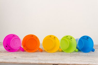 Çeşitli renk ahşap arka plan üzerinde gülümseyen, plastik bardak