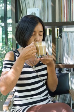 Beyaz ve siyah gömlek kafede kahve içme Asyalı kadın