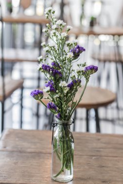 Ahşap bir masa üzerinde bir cam vazoda çiçekler.