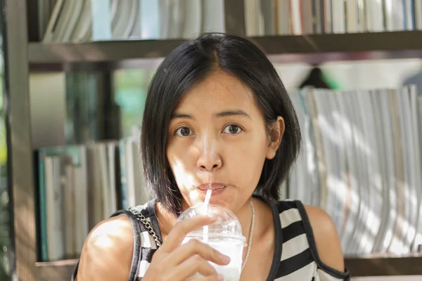 Asian woman in white and black shirts drinking coffee in the cafe