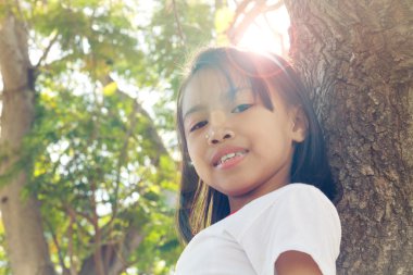 Mutlu sevimli Asya çocuk güneş parlama ile ağaca tırmanmak kadar kapatın.
