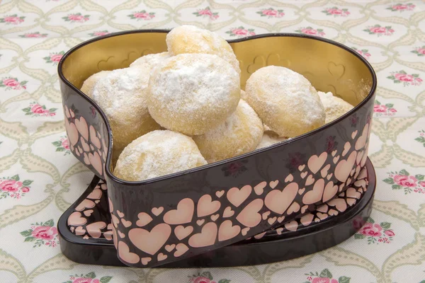 Homemade cookies in powdered sugar in a tin box in heart shape