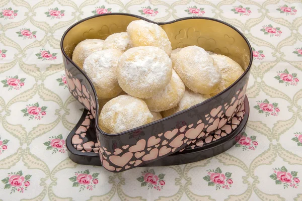 Kleine runde Kekse in Puderzucker in einer Blechdose in Herzform — Stockfoto