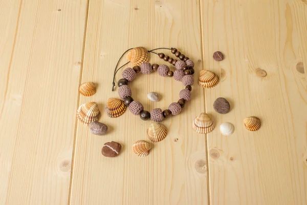 Crochet handmade beads, sea stones and seashells on a wooden