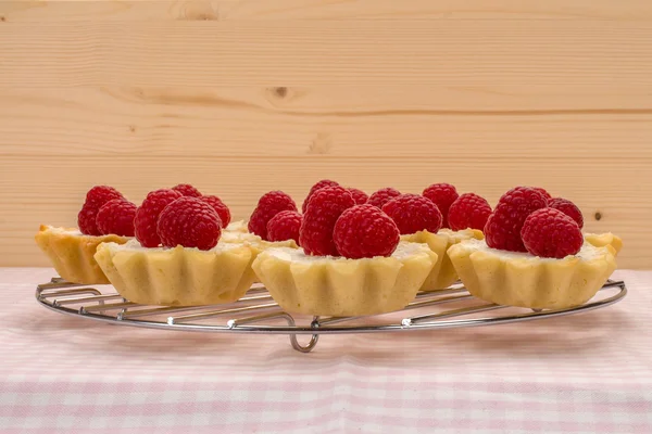 Homemade small cakes with fresh garden raspberries on wooden wal — Stock Photo, Image