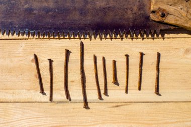 Paslı testere ve ahşap masa üzerinde on çivi