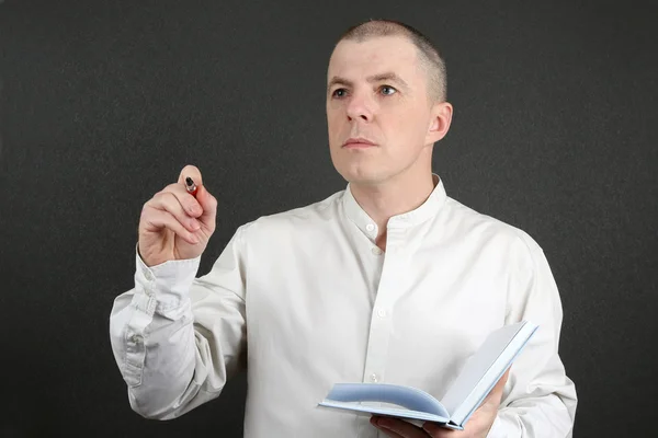 Hombre con un bloc de notas en la mano apuntando a la pluma en la dirección — Foto de Stock