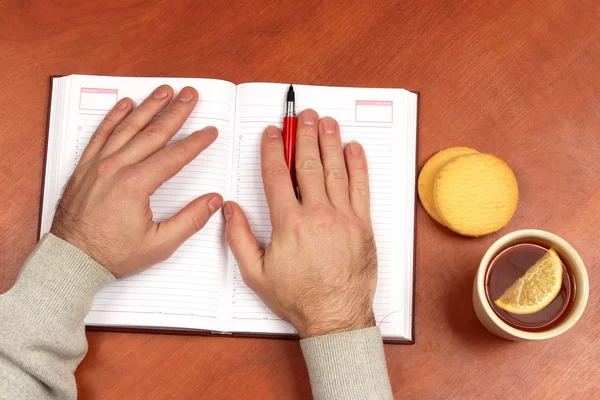 Dos manos con pluma roja acostado en un cuaderno en la oficina — Foto de Stock