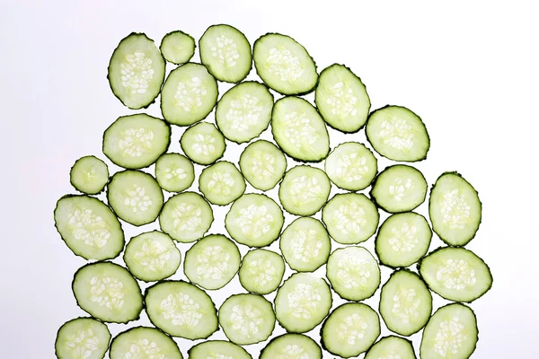 Şeffaf beyaz bir arka plan üzerinde salatalık ince dilimler kesip — Stok fotoğraf