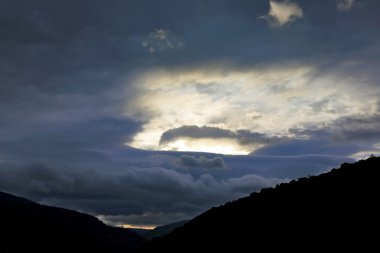 Dağların üzerinden gökyüzünde sulu günbatımı