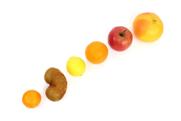 Различные фрукты на наклонной поверхности на белом фоне — стоковое фото