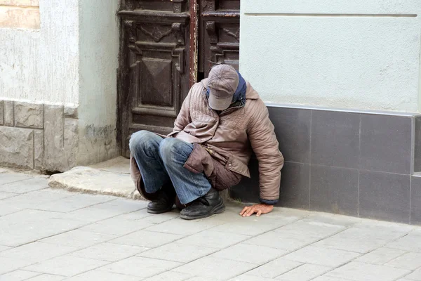 Armer Obdachloser sitzt in der Nähe der Hauswand — Stockfoto