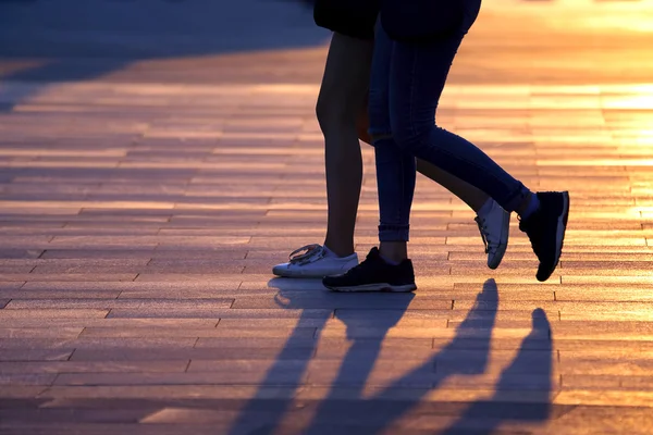 Pernas de duas pessoas andando no fundo da luz solar — Fotografia de Stock