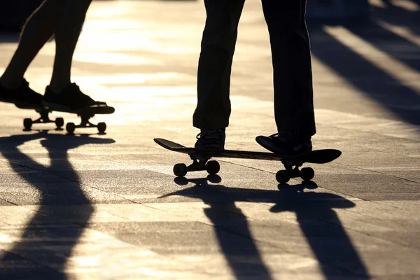 Silhouette von Menschen, die auf einem Skateboard in der Sonne fahren — Stockfoto
