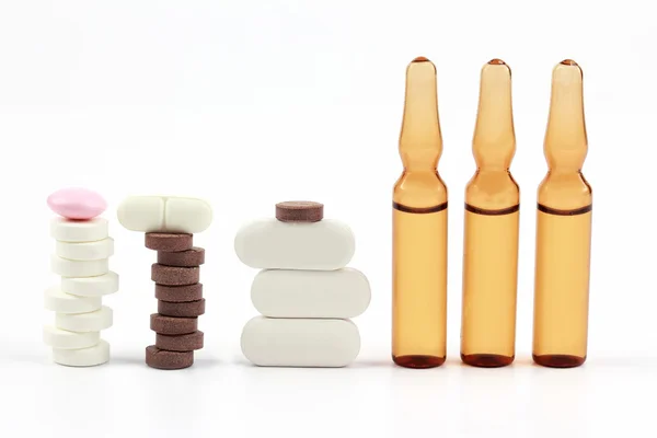 Лекарственные таблетки, ампулы для инъекций на белом фоне — стоковое фото
