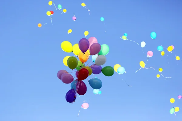Viele bunte Ballons fliegen in den blauen Himmel — Stockfoto