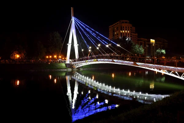 Refletido iluminação noturna da ponte no rio. Kharkov. . — Fotografia de Stock