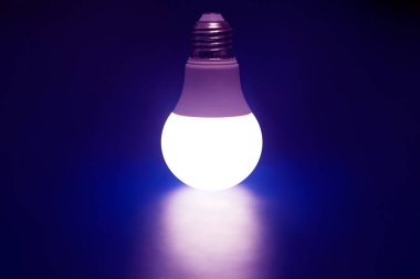 Koyu mavi arka planda parlayan LED lamba. Modern teknoloji ve elektrik.