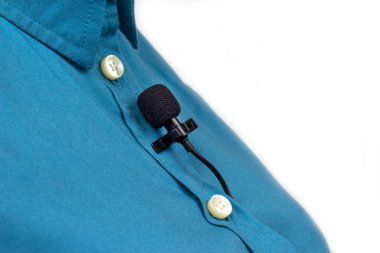 Lavalier mikrofon mavi bir kadın gömleğinin yakın plan klipsiyle korunuyor. Yoğunlaştırıcı mikrofondaki sesin ses kaydı.