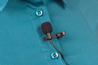 Yoğunlaştırıcı mikrofondan ses kaydı. Lavalier mikrofon bir kadının gömleğine yakın çekim şarjörüyle güvence altına alınmıştır..