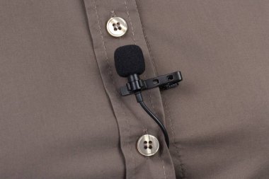 Yoğunlaştırıcı mikrofondan gelen sesin ses kaydı. Lavalier mikrofon kahverengi bir kadın gömleğinin yakın plan klipsiyle korunuyor.