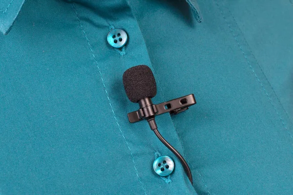 Yoğunlaştırıcı mikrofondan ses kaydı. Lavalier mikrofon bir kadının gömleğine yakın çekim şarjörüyle güvence altına alınmıştır..