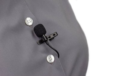 Lavalier mikrofon gri kadın gömleğinin yakın plan klipsiyle korunuyor. Yoğunlaştırıcı mikrofondaki sesin ses kaydı.